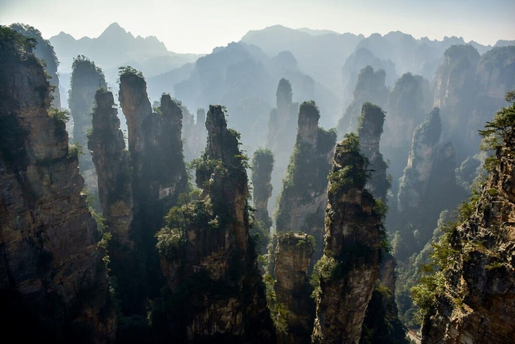 Montañas de piedra del Parque Forestal Nacional de Zhangjiajie, China, rodeadas de vegetación y niebla.